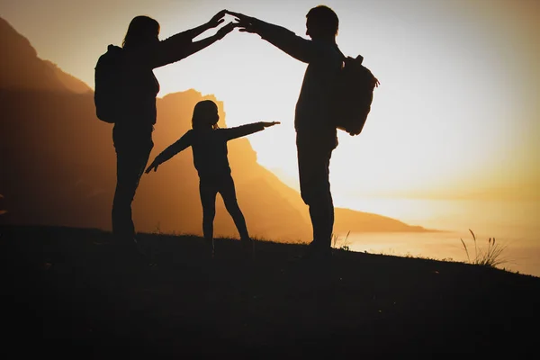 Счастливая семья мама, папа и маленькая девочка путешествуют в горах на закате — стоковое фото