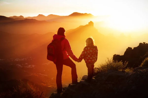 Мать с маленькой дочерью путешествует в горах заката — стоковое фото