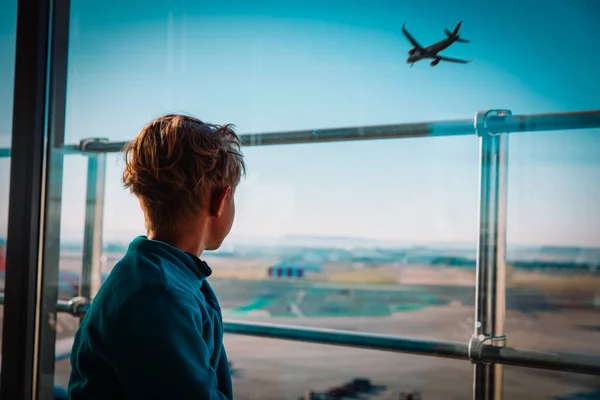 Хлопчик чекає в аеропорту, дивлячись на літаки, сімейні подорожі — стокове фото