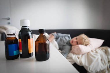 Evde ateşi olan hasta çocuk, masada ilaçlar