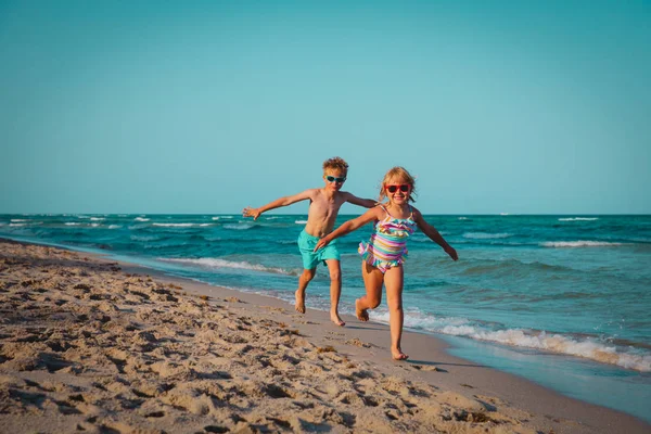 Feliz chico y chica ejecutar jugar en la playa — Foto de Stock