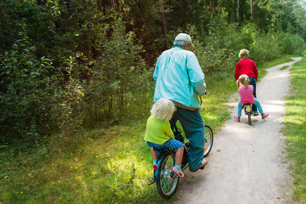 active senior granddad with kids riding bikes in nature
