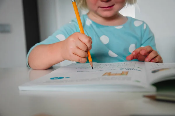 Liten flicka lära sig att hålla penna, skriva brev, göra läxor — Stockfoto