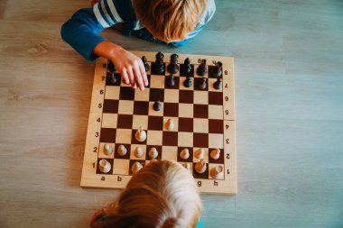 Küçük oğlan ve kız satranç oynar, çocuklar oynar ve öğrenir.