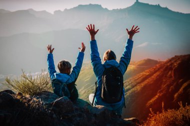 Mutlu baba ve oğul gün batımı dağlarda yürüyüş