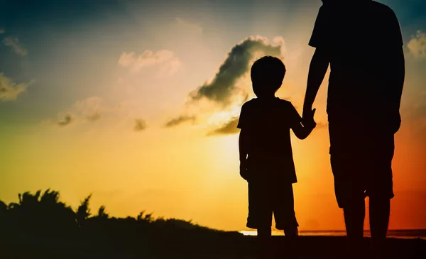 Sylwetka ojca i syna trzymających się za ręce przy zachodzie słońca — Zdjęcie stockowe
