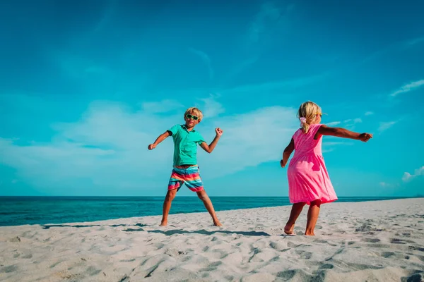 Kleine jongen en meisje dans op strand, kinderen genieten van vakantie op zee — Stockfoto
