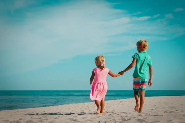 Kleine jongen en meisje lopen op strand — Stockfoto