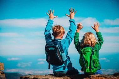 Mutlu çocuk ve kız dağlarda yürüyüş yapıyor, çocuklar tatilin tadını çıkarıyor.