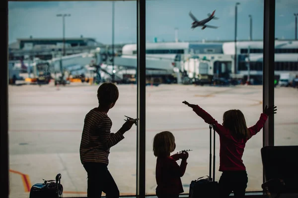 Barn leker leksaksplan på flygplatsen, pojke och flicka med bagage väntar — Stockfoto