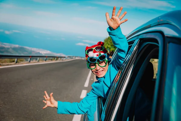 christmas car travel- happy child travel on road in winter