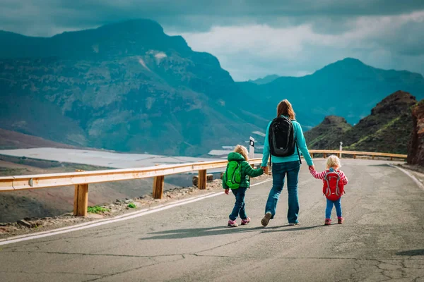 Mère avec deux enfants marchant sur la route dans les montagnes — Photo