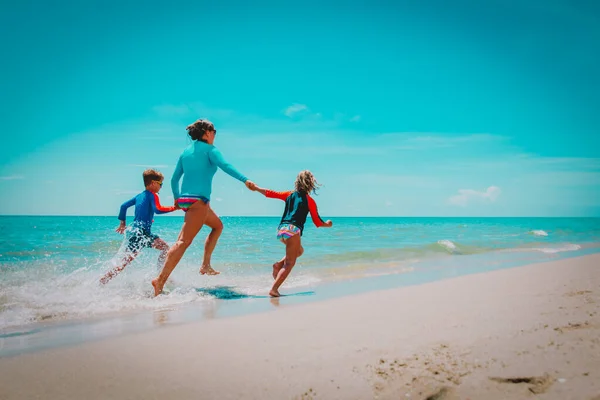 Мама с детьми играют с водой бегать по пляжу — стоковое фото