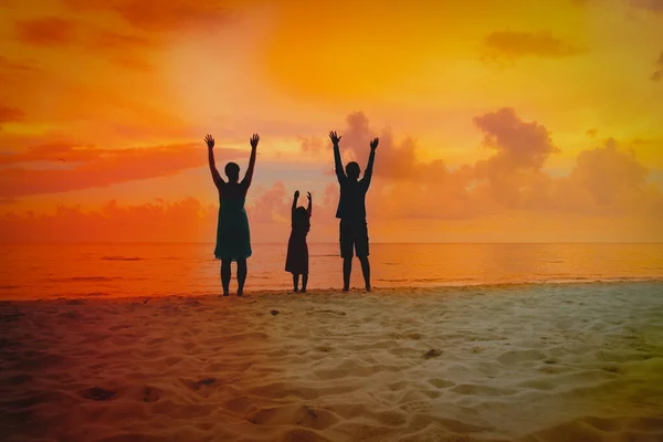 Família feliz com criança desfrutar de férias na praia do pôr do sol — Fotografia de Stock