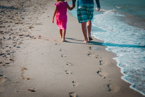 모래 위에 발자국을 남기고 해변을 걷고 있는 아버지와 딸 — 스톡 사진