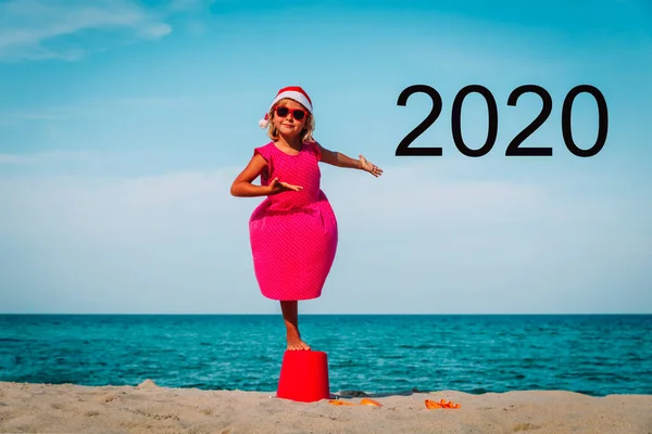 Happy little girl enjoy celebrating christmas and New Year 2020 on beach — Stock Photo, Image