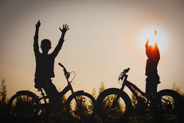 Menino feliz e menina andar de bicicleta no pôr do sol natureza — Fotografia de Stock