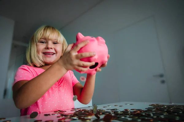Щаслива маленька дівчинка бере монети з скарбнички — стокове фото