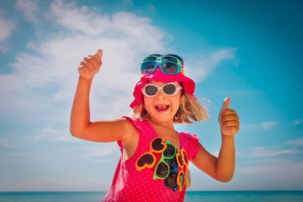 Cute happy girl try on sunglasses on beach — Stock Photo, Image