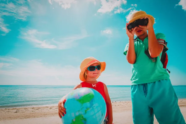 Kids travel on beach, boy and girl with globe and binoculars at sea — Stock Photo, Image