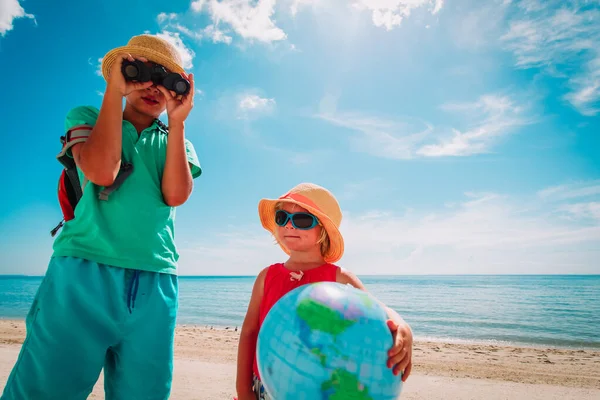 Kids travel on beach, boy and girl with globe and binoculars at sea — Stock Photo, Image