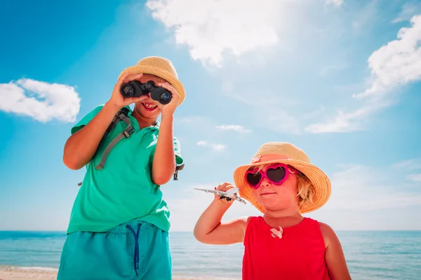 Kinder reisen am Strand, Junge und Mädchen mit Fernglas und Spielzeugflugzeug auf See — Stockfoto