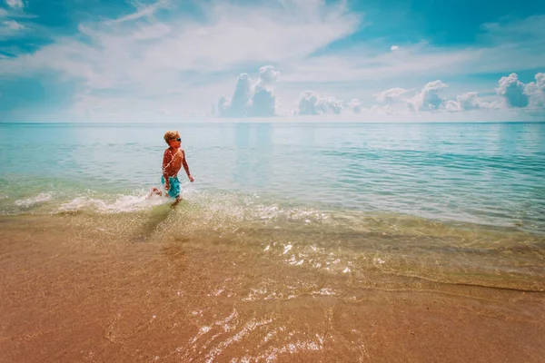 Felice ragazzo correre e giocare con le onde sulla spiaggia — Foto Stock