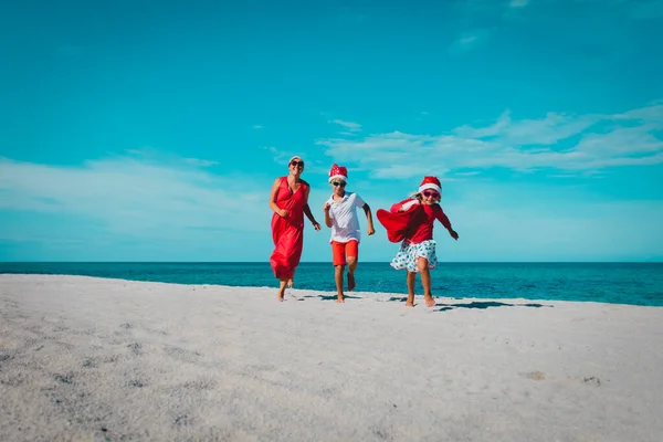 Glückliche Mutter mit Kindern laufen und haben Spaß am Weihnachtsstrand — Stockfoto