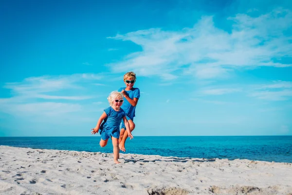 Gelukkig schattig jongen en meisje rennen op het strand — Stockfoto