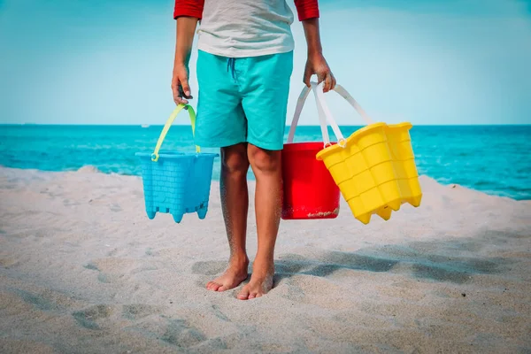 Ребенок держит игрушки на пляже, мальчик готов копать и играть с песком — стоковое фото