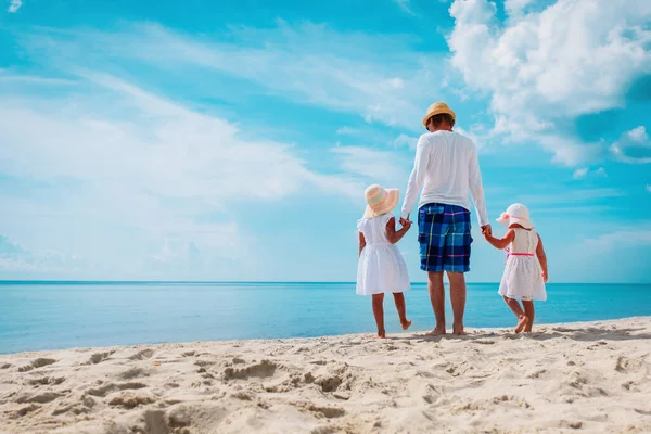 Vader met twee dochters wandelen op het strand — Stockfoto