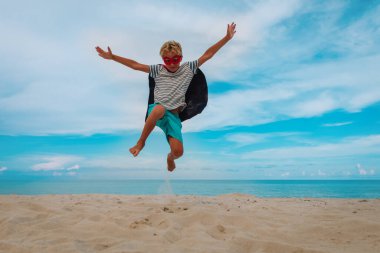 Mutlu çocuk plaj tatilinde süper kahramanı oynuyor.