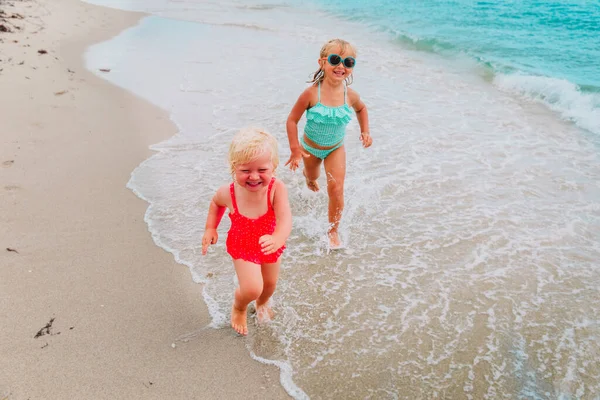 Счастливые девчонки играют с водой на пляже, дети веселятся — стоковое фото
