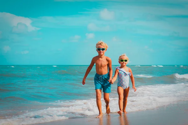 Мальчик и девочка гуляют по пляжу, дети купаются в море — стоковое фото