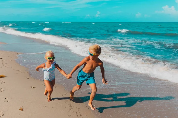 Meisje en jongen rennen op het strand, kinderen spelen met golven — Stockfoto