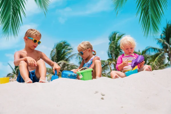 Kinder spielen mit Sand am Strand, Jungen und Mädchen im Tropenurlaub — Stockfoto