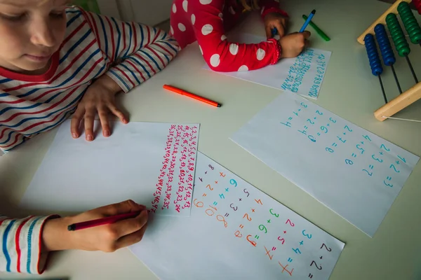 Niño y niña escribiendo números, niños haciendo la tarea — Foto de Stock