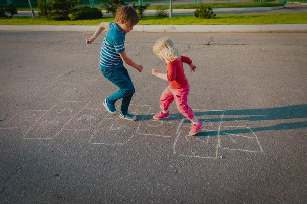 Crianças jogando hopscotch fora, menino e menina se divertir — Fotografia de Stock