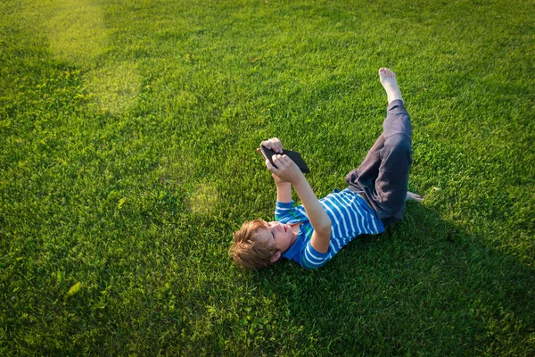 Pojke läsa bok om gräs, unge sommar lärande — Stockfoto