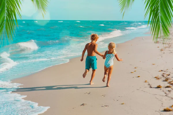 Šťastný chlapec a dívka běží na tropické pláži — Stock fotografie