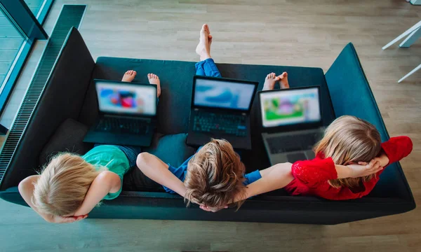 Niños con computadoras portátiles en casa, niños y niñas viendo películas en línea —  Fotos de Stock