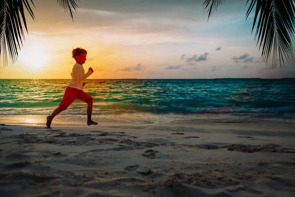 Šťastný malý chlapec běh na západ slunce tropické pláže — Stock fotografie