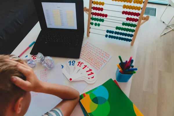 Niño aburrido de hacer su tarea con el ordenador portátil en casa . —  Fotos de Stock