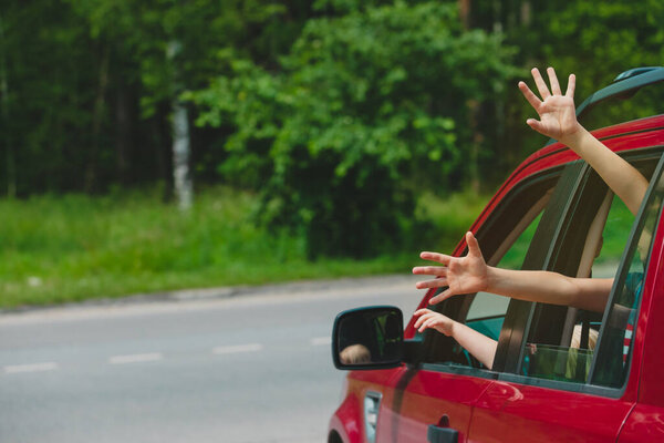 руки счастливых детей путешествуют на автомобиле по дороге на природе
