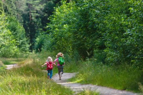 Glada små flickor med ryggsäckar springa i naturen — Stockfoto