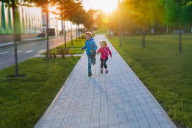 Mutlu kız ve erkek gün batımında şehirde, çocuklar eğleniyor.