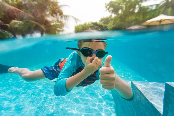 Mutlu küçük çocuk tropikal tatil köyünde suyun altında yüzüyor. — Stok fotoğraf