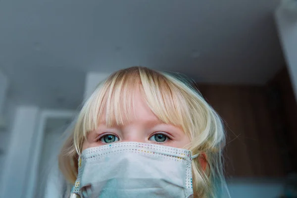Маленька дівчинка в захисній медичній масці залишається вдома — стокове фото