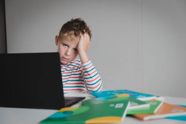 Bilgisayara bakan sıkkın ve üzgün bir genç çocuk, online iletişimden ve öğrenmekten bıkmış.