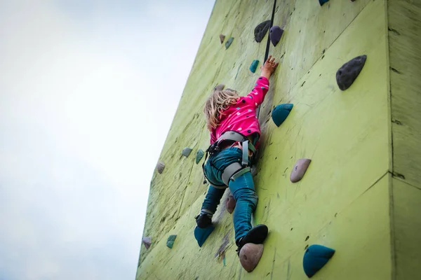 Dziewczynka wspina się na sztuczne głazy ściany na zewnątrz — Zdjęcie stockowe